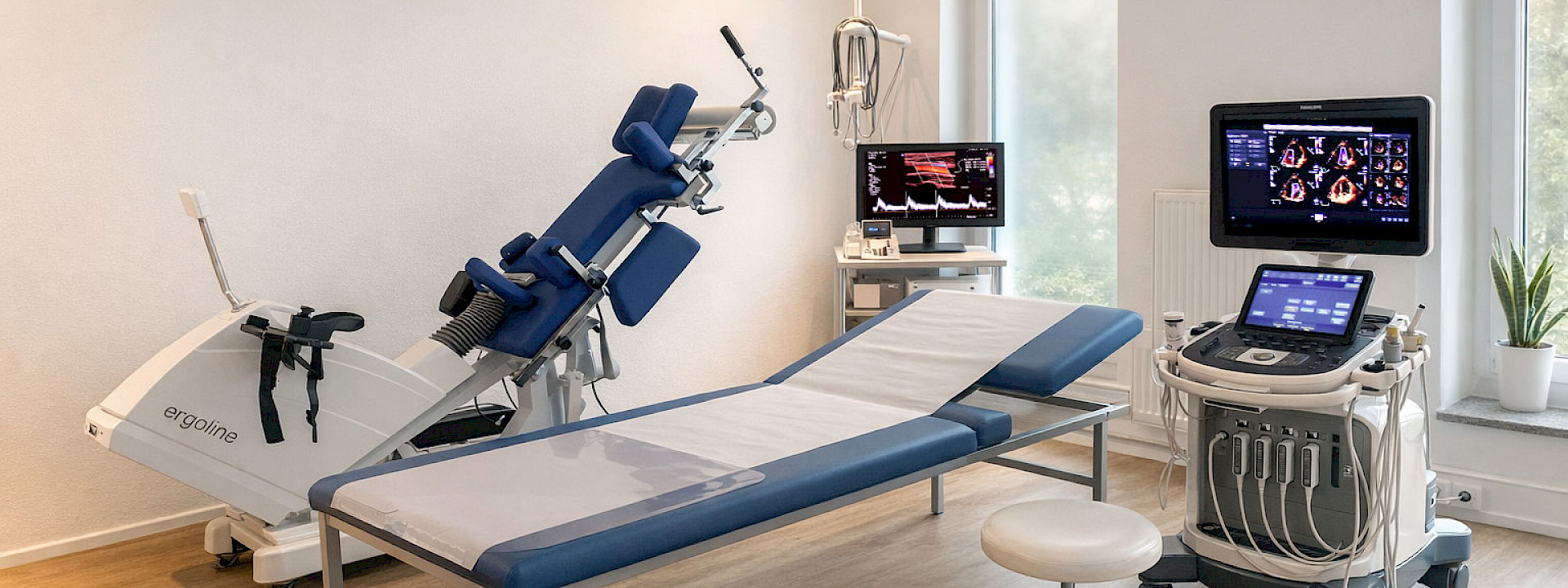 Heller, moderner Behandlungsraum in einer Arztpraxis mit Untersuchungsliege in der Mitte, daneben ein Ultraschallgerät mit Monitor, ein Hocker auf Rollen sowie weitere medizinische Geräte. Links steht ein ergonomisches Trainings- oder Therapiegerät, im Hintergrund ein Schreibtisch mit Computer und große Fenster mit Tageslicht.
